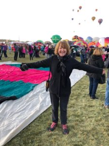 Author Minrose Gwin standing in front of hot air balloons